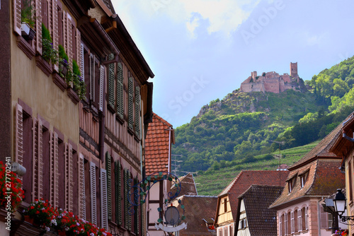 View through an alley to the houses and a castle in the background in Alsace, France.