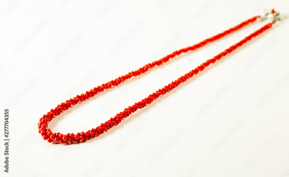 3連の赤珊瑚のネックレスと白バック