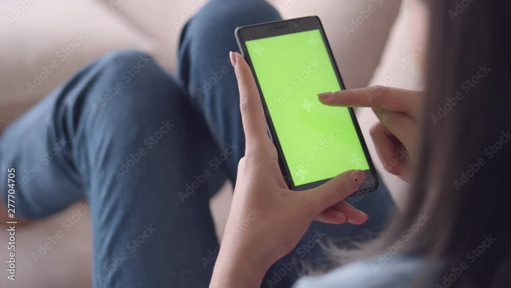 Beautiful young asian woman viewing green screen on mobile phone browsing social media While sitting sofa in living room at home. business woman enjoying watching video on smartphone. Beautiful young asian woman viewing green screen on mobile phone browsing social media While sitting sofa in living room at home. business woman enjoying watching video on smartphone.