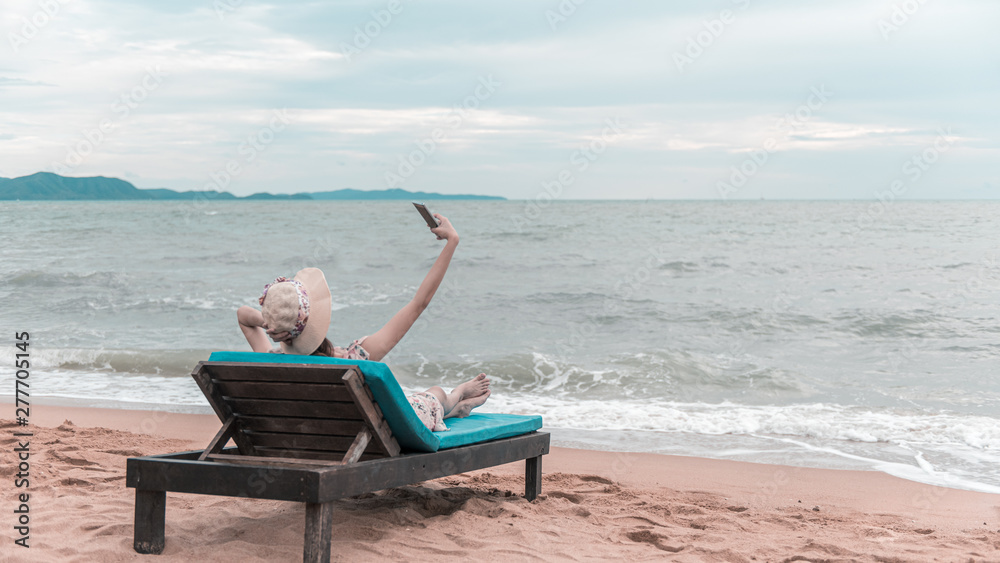 Traveller woman selfie on the beach chair, summer beach vacation concept.