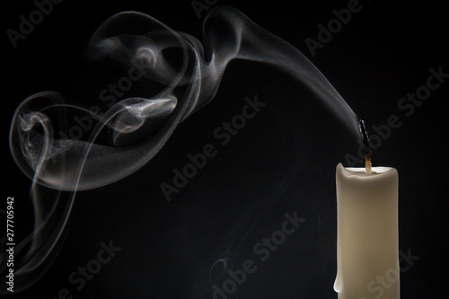 Smoke and extinct candle on a black background