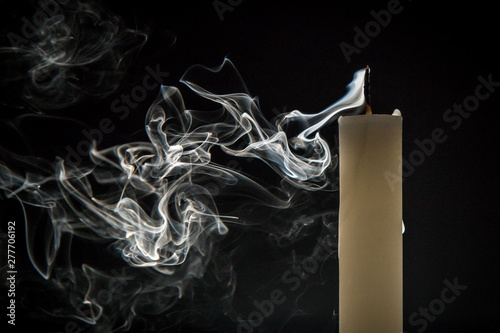 Smoke and extinct candle on a black background