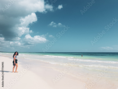 girl walking on white sandy beach of caribbean in Tulum, Mexico