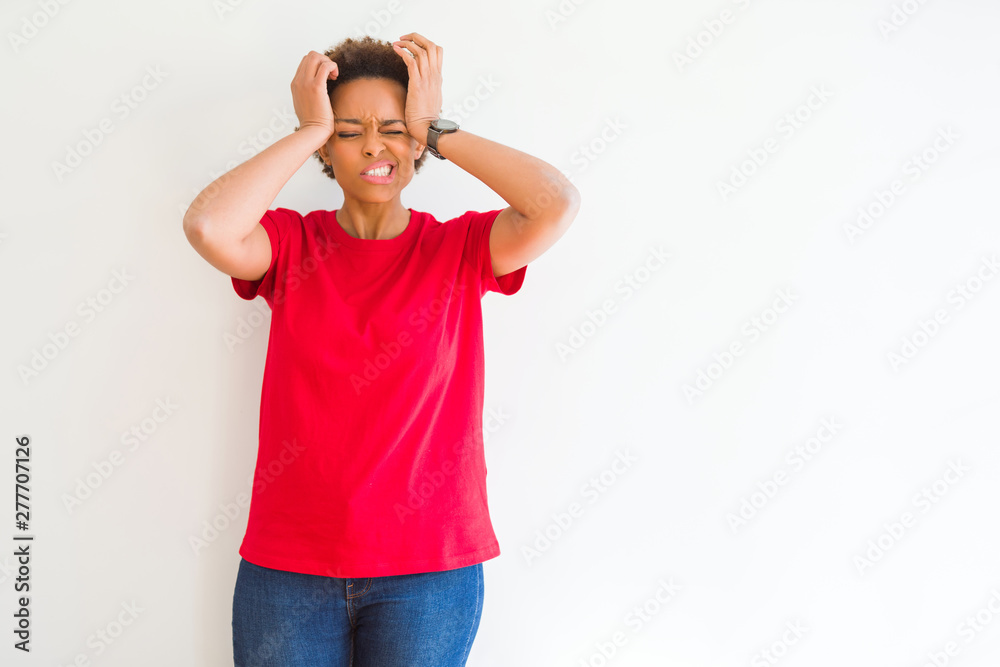 Young beautiful african american woman over white background suffering from headache desperate and stressed because pain and migraine. Hands on head. Young beautiful african american woman over white background suffering from headache desperate and stressed because pain and migraine. Hands on head.