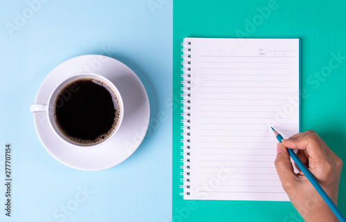Back to school. Black Coffee and notebook with colored pencil on pastel blue and green table background. Copy space for text.