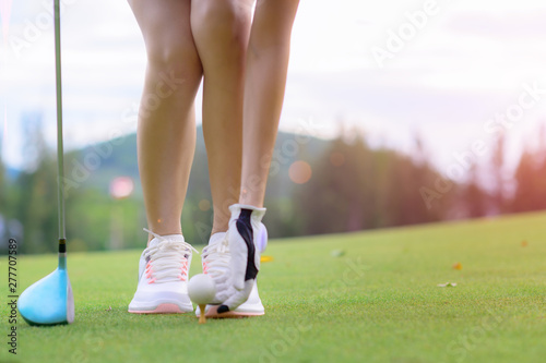 young woman golf player laying golf ball on the wooden tee, prepare and ready to hit the ball away to fairway destination winning