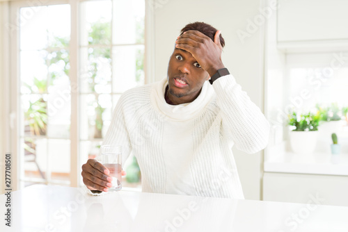 African american man driking a fresh glass of water stressed with hand on head  shocked with shame and surprise face  angry and frustrated. Fear and upset for mistake.