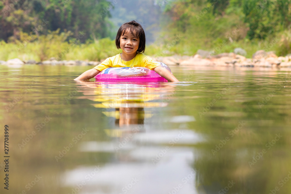 Little Asian girl with pool ring floating in river Little Asian girl with pool ring floating in river
