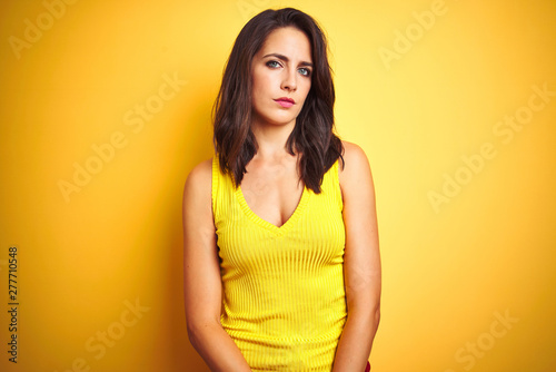 Young beautiful woman wearing t-shirt standing over yellow isolated background Relaxed with serious expression on face. Simple and natural looking at the camera.