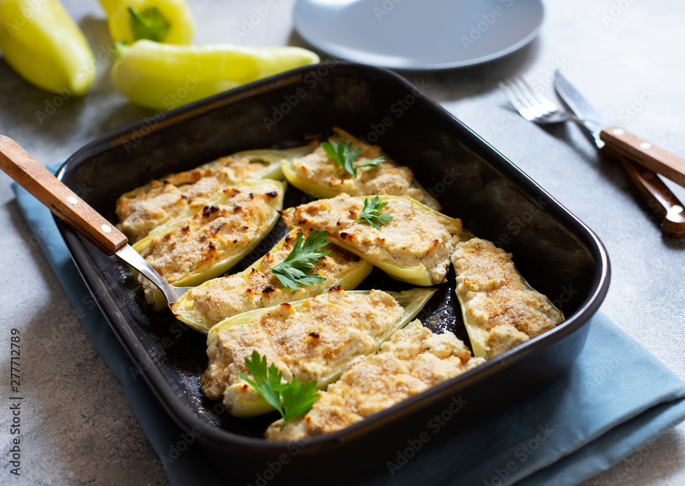 Roasted peppers stuffed with cheese and herbs in baking tray. Healthy Meatless Meal. Characteristic dish of the Balkan cuisine. Serbian cuisine. Gray background, close-up, selective focus