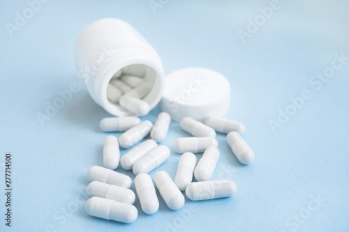 prescription opioids spilling from white bottle with copy space. on a blue background