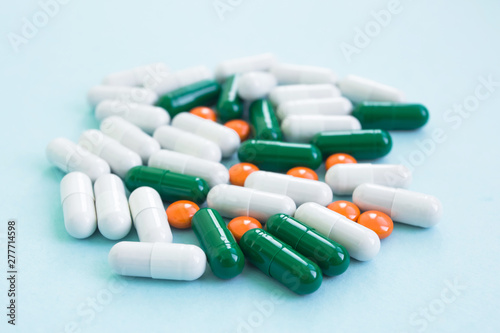 A pile of tablets of different colors and shapes on a blue background. Creative medicine for health/medical problem, drug interaction, medication error and pharmaceutical concept.