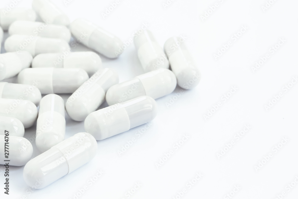  Several white capsules of drugs and pills on a white isolated background.