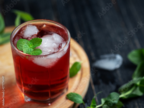 Red alcoholic cocktail with ice and mint in a glass