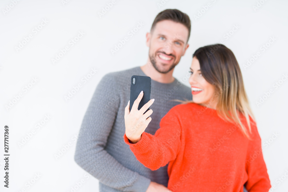 Beautiful young couple in love, kissing and hugging each other using smarthpone Beautiful young couple in love, kissing and hugging each other using smarthpone