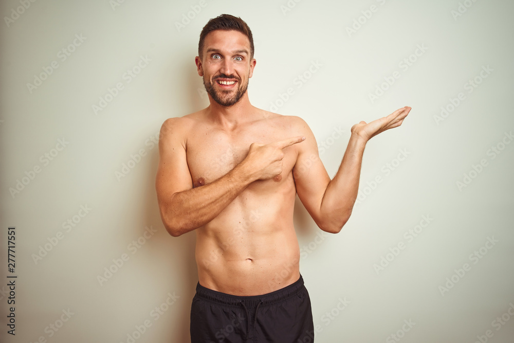 Fototapeta premium Young handsome shirtless man over isolated background amazed and smiling to the camera while presenting with hand and pointing with finger.