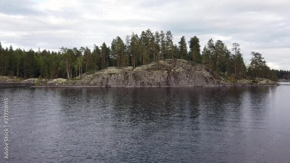 Small island with steep rock wall in lake Saimaa, Finland.