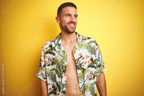 Wallpaper Mural Handsome man wearing summer hawaiian flowers shirt over yellow isolated background looking away to side with smile on face, natural expression. Laughing confident. Torontodigital.ca