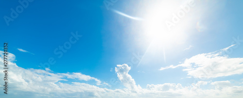 Sun shining in a blue sky with white clouds