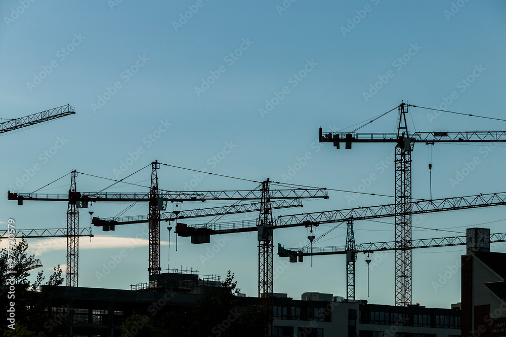 Silhouette of construction tower crane against blue evening sky