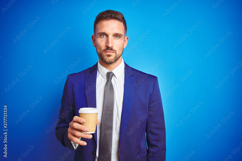 Young handsome business man drinking a coffee on a paper cup over blue isolated background with a confident expression on smart face thinking serious Young handsome business man drinking a coffee on a paper cup over blue isolated background with a confident expression on smart face thinking serious