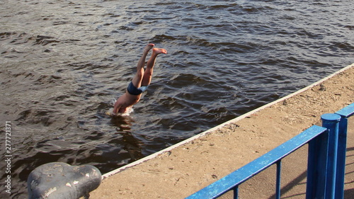 Man swimmer dives from the pier into the water - the danger of swimming in unequipped places photo