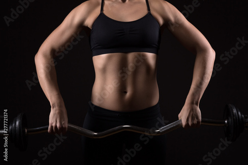 Woman with perfectly trained body is exercising on a barbell. Fitness, workout and training concept.