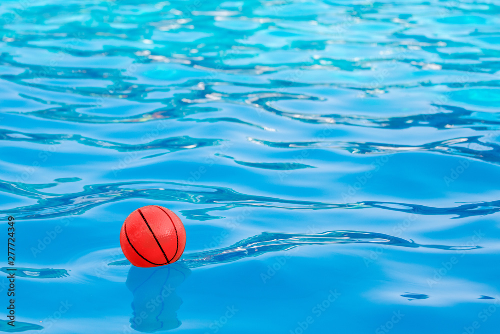 Red ball on the blue water of the pool_
