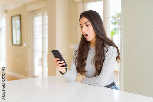 Young woman using smartphone sending a message scared in shock with a surprise face, afraid and excited with fear expression