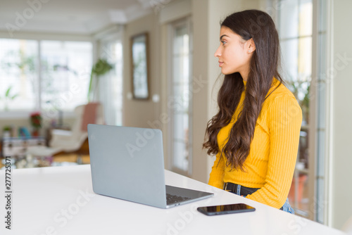 Young woman using computer laptop looking to side, relax profile pose with natural face with confident smile.