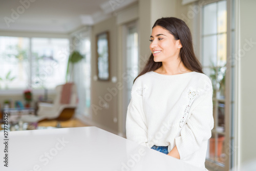 Young beautiful woman at home on white table looking away to side with smile on face, natural expression. Laughing confident. Free Download Young beautiful woman at home on white table looking away to side with smile on face, natural expression. Laughing confident. - GFXLoad