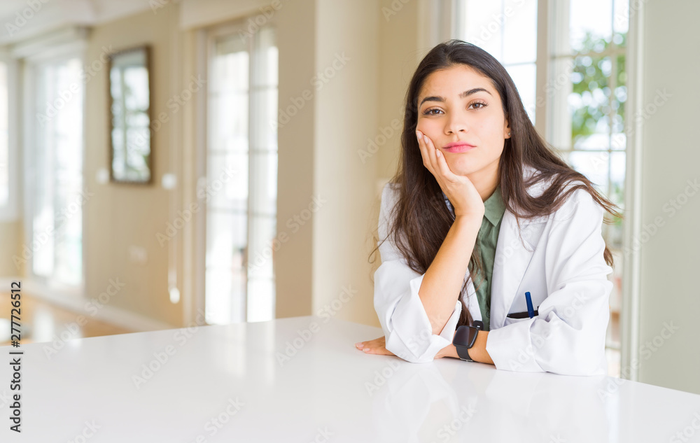 Young woman wearing medical coat at the clinic as therapist or doctor thinking looking tired and bored with depression problems with crossed arms. Young woman wearing medical coat at the clinic as therapist or doctor thinking looking tired and bored with depression problems with crossed arms.