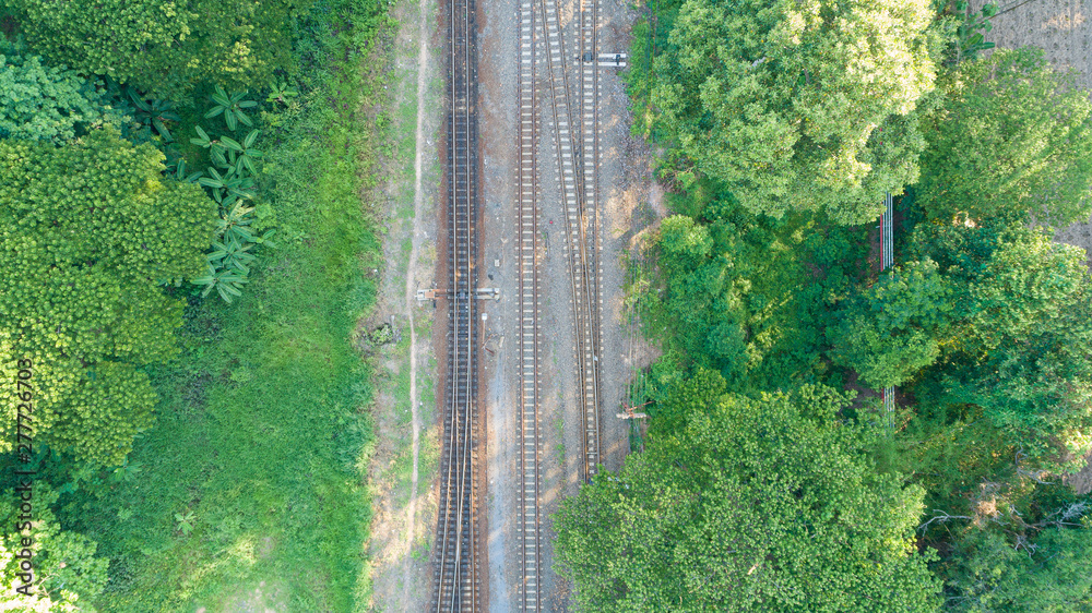 Aerial view of railway track through countryside, top view pov of rails as abstract background.