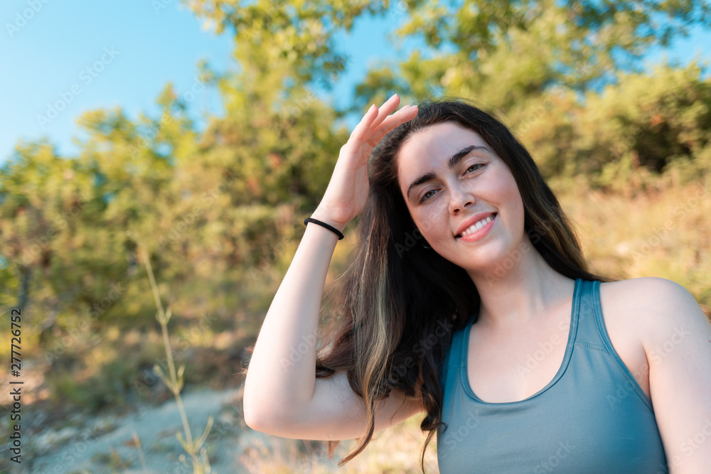Young beautiful woman smiling and posing for the camera. Forest in the background. Sports, fitness and healthy lifestyle tracking concept