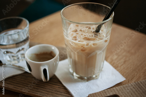 Morning cofee lifestyle. Cup of espresso and a glass of ice latte standing on the wooden desk.