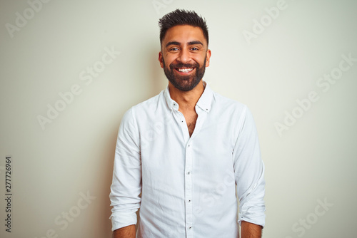 Young indian man wearing elegant shirt standing over isolated white background with a happy and cool smile on face. Lucky person.
