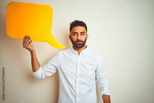Young arab indian hispanic man holding speech bubble over isolated white background with a confident expression on smart face thinking serious