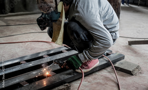 Industrial Worker at the factory welding closeup. Electric wheel grinding on steel structure in factory. photo