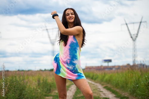 Young beautiful woman in colored tunic posing against the background of a meadow field