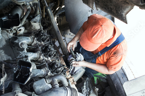 Mechanic repairs a truck. adjustment of valves of the diesel motor. Replacement nozzles. photo