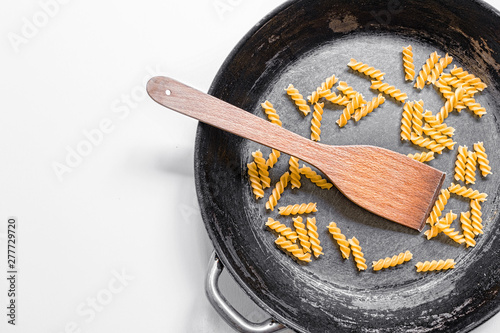 Fresh not boiled macaroni in the old frying pan. photo