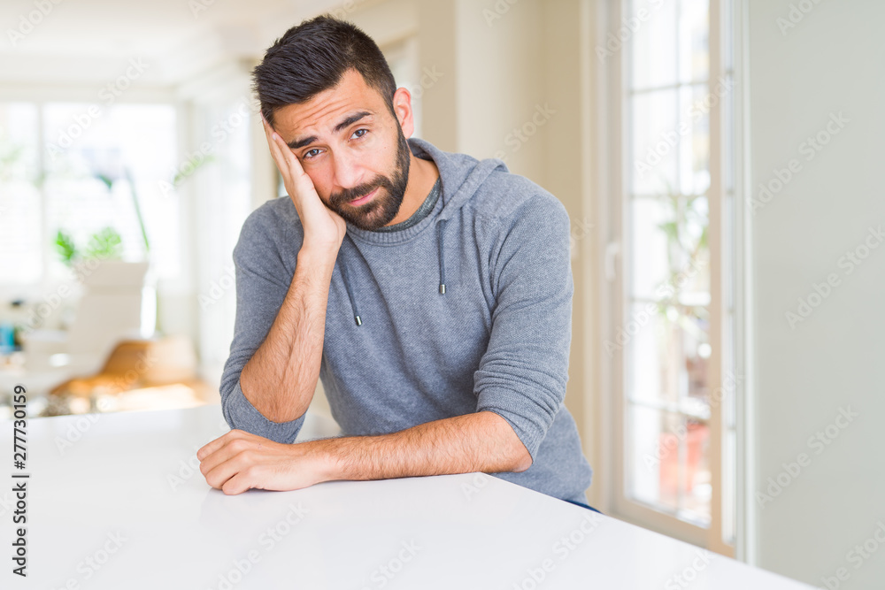 Handsome hispanic man wearing casual sweatshirt at home thinking looking tired and bored with depression problems with crossed arms.