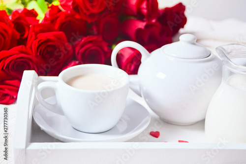 Close up of cup of tea with red rose on the white tray