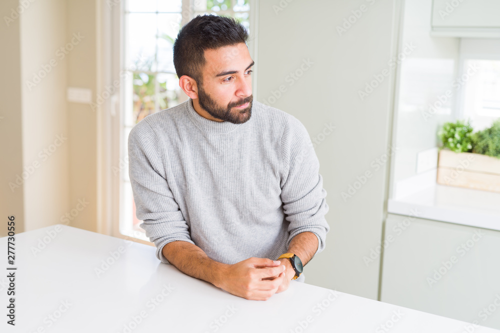Handsome hispanic man wearing casual sweater at home looking to side, relax profile pose with natural face with confident smile.