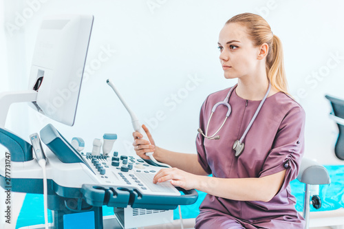 Young female londe doctor with black glasses. Ultrasound scanner with transvaginal sensor in the hands of a doctor. Diagnostics. Sonography. photo