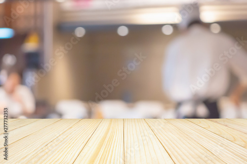 Empty wood table top with Chef cooking in restaurant kitchen abstract blurred defocused background
