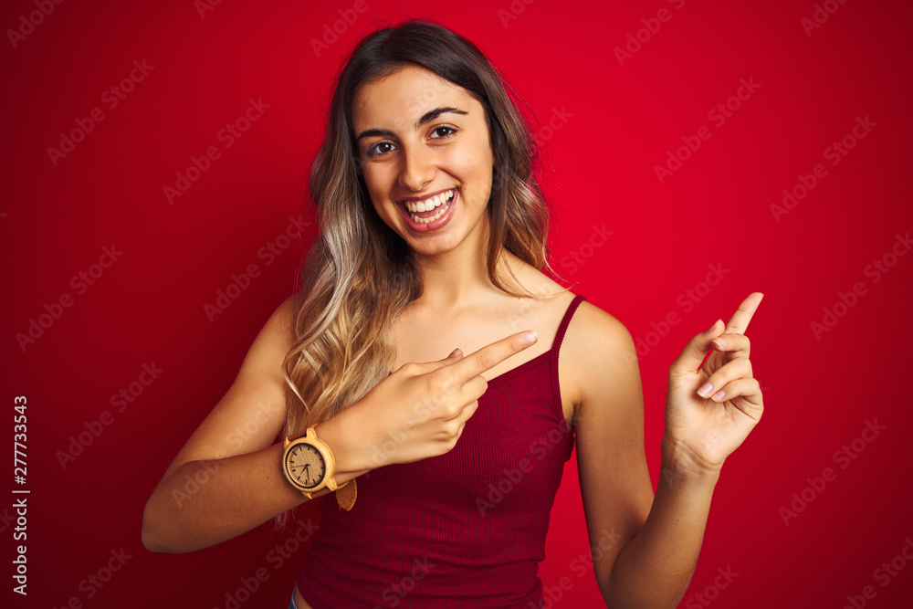 Young beautiful woman wearing a t-shirt over red isolated background smiling and looking at the camera pointing with two hands and fingers to the side.