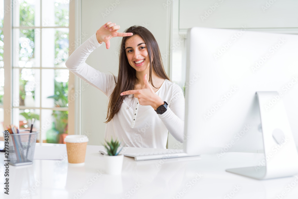 Beautiful young woman working using computer smiling making frame with hands and fingers with happy face. Creativity and photography concept. Beautiful young woman working using computer smiling making frame with hands and fingers with happy face. Creativity and photography concept.