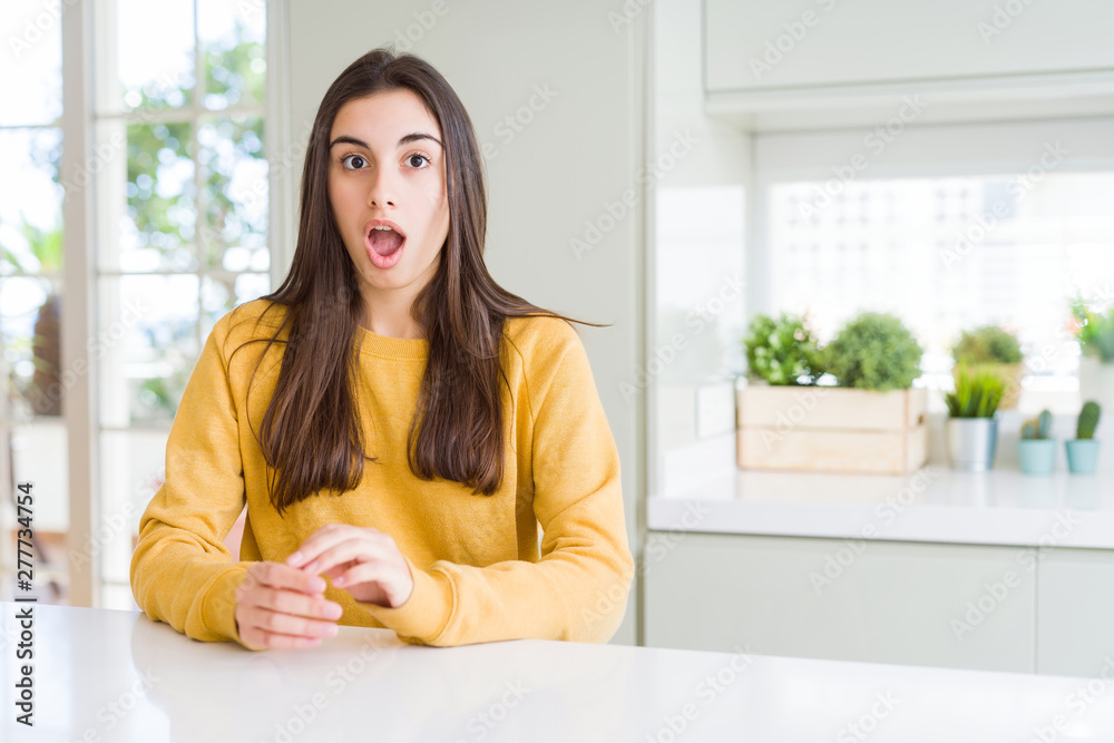 Beautiful young woman wearing yellow sweater afraid and shocked with surprise expression, fear and excited face. Beautiful young woman wearing yellow sweater afraid and shocked with surprise expression, fear and excited face.