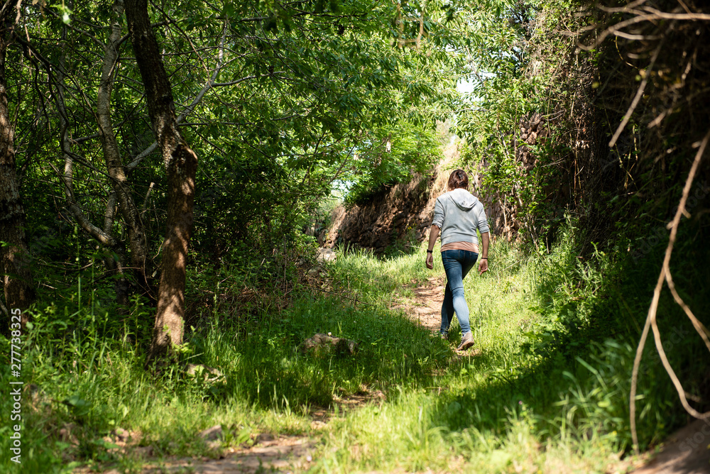Obraz premium Woman walking on a forest trail.